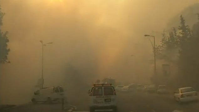 سيارة اسعاف تمر في شوارع حيفا المغطاة في الدخان  بينما يحاول رجال الاطفاء احماد حريق هائل ينتشر في المدينة، 24 نوفمبر 2016 (screen capture: Channel 10)