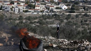 متظاهر فلسطيني ينظر الى اطارات مشتعلة خلال مواجهات مع قوات الامن الإسرائيلية بالقرب من مستوطنة كيدزميم في الضفة الغربية، 9 ديسمبر 2016 (AFP/JAAFAR ASHTIYEH)