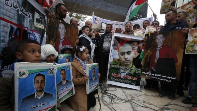 فلسطينيون يحملون ملصقات خلال مظاهرة في مدينة الخليل بالضفة الغربية، اثناء صدور الحكم ضد الجندي الإسرائيلي ايلور عزاريا الذي قتل عبد الفتاح الشريف، 4 يناير 2017 (AFP/HAZEM BADER)
