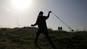 متظاهر فلسطيني يستخدم مقلاع لرشق الحجارة باتجاه قوات الامن الإسرائيلية خلال اشتباكات امام سجن عوفر في الضفة الغربية، 5 فبراير 2016 (AFP / ABBAS MOMANI)