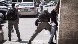 عنصر من شرطة حرس الحدود الإسرائيلية يقوم بتفتيش شاب فلسطيني عند باب العامود في البلدة القديمة في القدس، 20 سبتمبر، 2016. (Sebi Berens/Flash90)