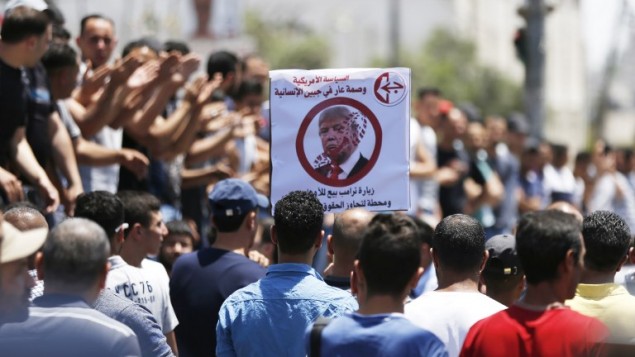 فلسطينيون يرفعون لافتات عليها صورة الرئيس الامريكي دونالد ترامب خلال مظاهرة دعم للاسرى الفلسطينيين المضربين عن الطعام في السجون الإسرائيلية وايضا لإدانة زيارة الرئيس الامريكي دونالد ترامب لإسرائيل والاراضي الفلسطينية في حاجز قلنديا، 22 مايو 2017 (ABBAS MOMANI / AFP)