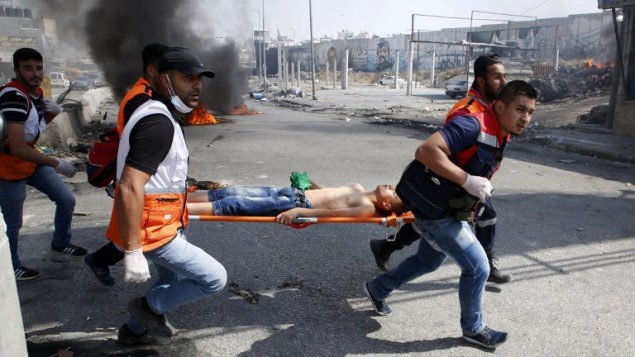 مسعفون فلسطينيون يقومون بإخلاء متظاهر مصاب خلال اشتباكات مع جنود اسرائيليين بعد مظاهرة دعم للاسرى الفلسطينيين المضربين عن الطعام في السجون الإسرائيلية وايضا لإدانة زيارة الرئيس الامريكي دونالد ترامب لإسرائيل والاراضي الفلسطينية في حاجز قلنديا، 22 مايو 2017 (ABBAS MOMANI / AFP)