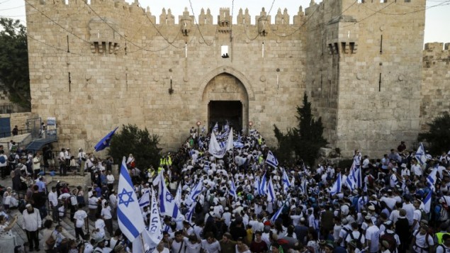 اسرائيليون يلوحون بالاعلام الإسرائيلية في باب العامود، خلال مسيرة احتفال بيوم القدس، في الذكرى الخمسين لتوحيد المدينة بعد حرب 1967، 24 مايو 2017 (AFP PHOTO / Menahem KAHANA)