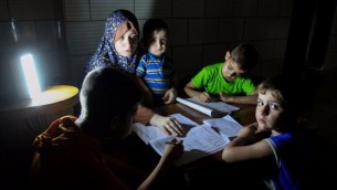 أطفال فلسطينيون يدرسون على ضوء المصباح خلال انقطاع للكهرباء في رفح جنوب قطاع غزة، 18 مايو، 2016. (Abed Rahim Khatib/Flash90)