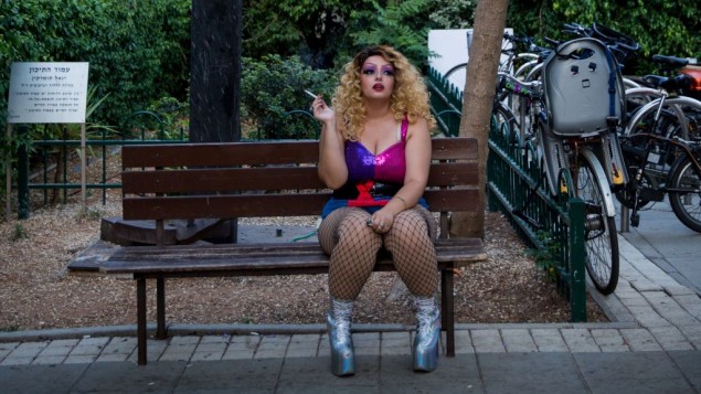 عارض في Wigstock Drag Queen Show يدخن سيجارة قبل العرض في حديقة مئير في تل ابيب، ضمن احتفالات اسبوع الفخر المثلي، 7 يونيو 2017 (Miriam Alster/FLASH90)