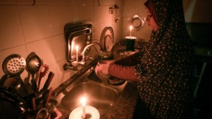 امرأة فلسطينية تغسل الصحون على ضوء الشموع في منزلها المؤقت في مخيم رفح للاجئين في جنوب قطاع غزة في 12 يونيو / حزيران 2017.  (Abed Rahim Khatib/Flash90)