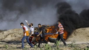 متظاهرون ومسعفون فلسطينيون يحملون مصابا خلال مواجهات مع القوات الإسرائيلية بالقرب من السياج الحدودي شرقي مخيم جباليا، في 23 يونيو، 2017. (AFP/MOHAMMED ABED)