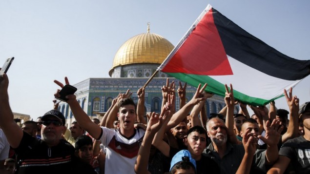 مصلون يرفعون العلم الفلسطيني ويومضون بادرة النصر أمام قبة الصخرة في الحرم القدسي في 27 يوليو / تموز 2017. (AFP Photo/Ahmad Gharabli)