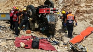 مسعفون ورجال إطفاء يقوموم بسحب رجلين من شاحنة انقلبت على طريق سريع شمال مدينة إيلات، 13 يونيو، 2017. (نجمة داوود الحمراء)