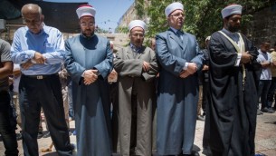 مسؤولون في الأوقاف الإسلامية وأخرون يستعدون للصلاة خارج الحرم القدسي، في البلدة القديمة في مدينة القدس، ويرفضون الدخول إلى المجمع عبر البوابات الإلكترونية التي وضعتها إسرائيل بعد هجوم وقع في المكان، 16 يوليو، 2017. (Yonatan Sindel/Flash90)