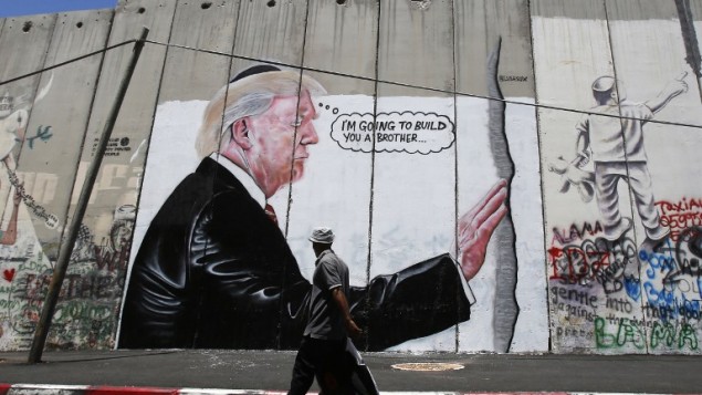 رجل فلسطيني يمر بجانب رسمة جدارية تصور الرئيس الأمريكي دونالد ترامب على الجدار الفاصل الإسرائيلي في بيت لحم بالضفة الغربية في 4 أغسطس / آب 2017. (AFP/Musa Al Shaer) رجل فلسطيني يمر بجانب رسمة جدارية تصور الرئيس الأمريكي دونالد ترامب على الجدار الفاصل الإسرائيلي في بيت لحم بالضفة الغربية في 4 أغسطس / آب 2017. (AFP/Musa Al Shaer)