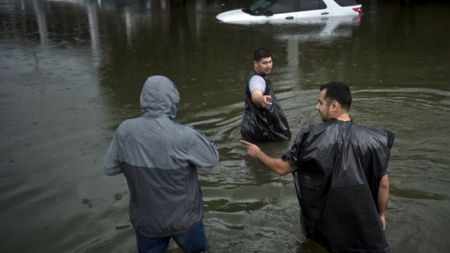 اشخاص يمشون خلال الفيضانات في شوارع هيوستن، تكساس في اعقاب الاعصار هارفي، 27 اغسطس 2017 (AFP PHOTO / Brendan Smialowski)