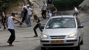 متظاهرون يلقون بالحجارة على مركبة في حي سلون في القدس في عام 2011. (Yonatan Sindel / Flash90)