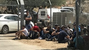 عمال فلسطينيون يجلسون في مستوطنة هار أدار بعد إخراجهم من المنطقة من قبل الجنود في أعقاب هجو وقع عند مدخل المستوطنة في 26 سبتمبر، 2017. (Jacob Magid/Times of Israel)