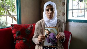 منال السيد تحمل صورة لابنها هشام الذي يعتقد أن جماعة حماس تحتجزه  في غزة عام 2016. (Yoav Lemmer/AFP)
