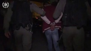 الشرطة تعتقل أحد سكان حي العيساوية في القدس الشرقية للاشتباه بمشاركته في احتجاجات عنيفة في إطار مداهمة ليلية واسعة، 23 أكتوبر، 2017.  (لقطة شاشة: الشرطة الإسرائيلية)