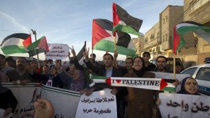 فلسطينيون يلوحون باعلام فلسطينية خلال مظاهرة في غزة، 22 ابريل 2014 (AFP/Mahmud Hams)