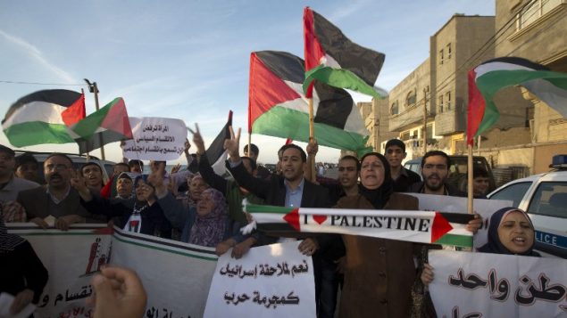 فلسطينيون يلوحون باعلام فلسطينية خلال مظاهرة في غزة، 22 ابريل 2014 (AFP/Mahmud Hams)