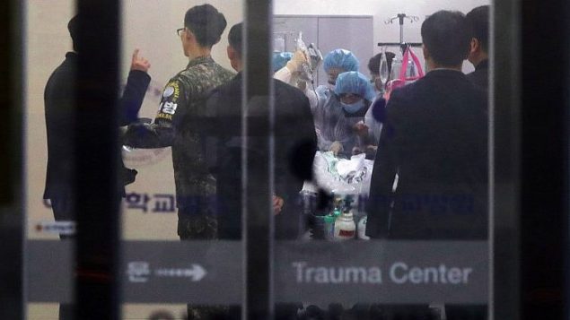 جندي كوري جنوبي ينظر بينما يعالج طاقم طبي شخص مجهول يعتقد انه جنودي كوري شمالي فر الى الجنوب، في سيول، 13 نوفمبر 2017 (AFP/YONHAP)