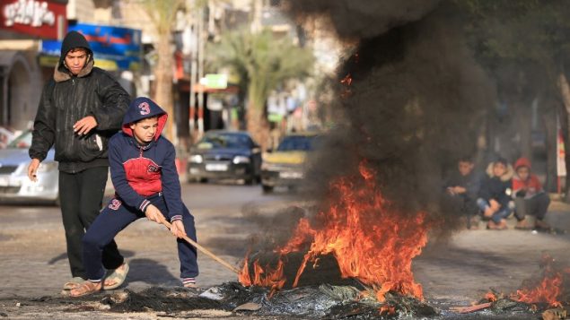 شبان فلسطينيون يشعلون اطارات خلال مظاهرة ضد اعتراف الرئيس الامريكي دونالد ترامب بالقدس كعاصمة اسرائيل، في مدينة غزة، 7 ديسمبر 2017 (MOHAMMED ABED/AFP)