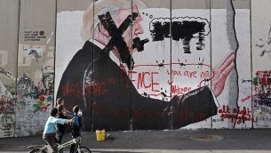 أطفال فلسطينيون ينظرون إلى رسم غرافيتي للرئيس الأمريكي دونالد ترامب وشعارات ضد نائب الرئيس مايك بنس على الجدار الفاصل الإسرائيلي في مدينة بيت لحم في الضفة الغربية خلال مواجهات بين محتجين فلسطينيين والقوات الإسرائيلية عند حاجز إسرائيلي، 7 ديسمبر، 2017. (AFP/Thomas Coex)