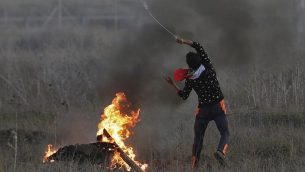 محتج فلسطيني يلقي بحجر اتجاه القوات الإسرائيلية خلال مواجهات على الحدود بين إسرائيل وغزة شرقي مدينة غزة في 9 ديسمبر، 2017،  في أعقاب قرار الرئيس الأمريكي دونالد ترامب الإعتراف بالقدس عاصمة لإسرائيل. (AFP/Mahmud Hams)