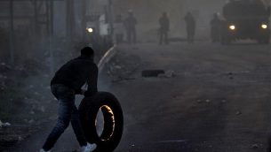 متظاهر فلسطيني يدفع بإطار مشتعل باتجاه القوات الإسرائيلية خلال مواجهات في مدينة نابلس في الضفة الغربية، في 9 ديسمبر، 2017، في أعقاب تظاهرات ضد قرار الرئيس الأمريكي دونالد ترامب الإعتراف بالقدس عاصمة لإسرائيل. (AFP PHOTO/ AAFAR ASHTIYEH)