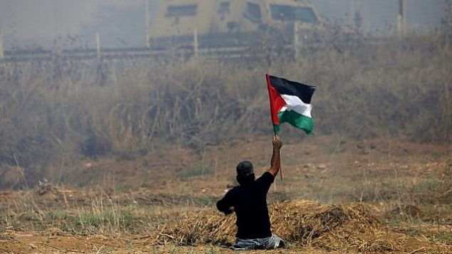 الشاب الفلسطيني إبراهيم أبو ثريا يلوح بالعلم الفلسطيني خلال مواجهات مع جنود إسرائيليين بالقرب من السياج الحدودي شرقي مدينة غزة، 19 مايو، 2017. (AFP PHOTO / MOHAMMED ABED/File)