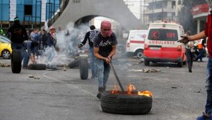 محتجون فلسطينيون يحرقون الإطارات أثناء اشتباكات مع حرس الحدود الإسرائيليين شمال رام الله في الضفة الغربية في 22 ديسمبر / كانون الأول 2017. (Abbas Momani/AFP)