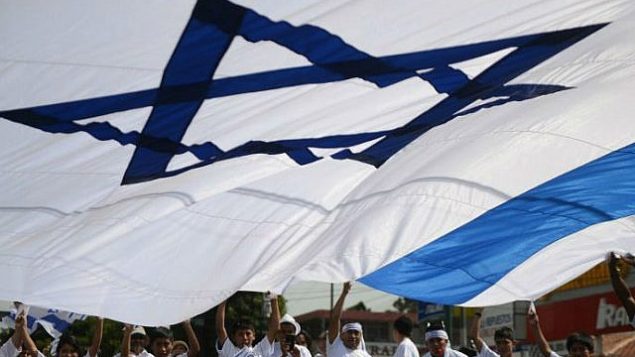 مجموعة مؤيدة لإسرائيل تلوح بعلم إسرائيلي عملاق خلال تظاهرة تضامن مع إسرائيل خلال حملة عسكرية في غزة في شوارع غواتيمالا سيتي في 3 أغسطس، 2014. ( AFP/ Johan ORDONEZ)