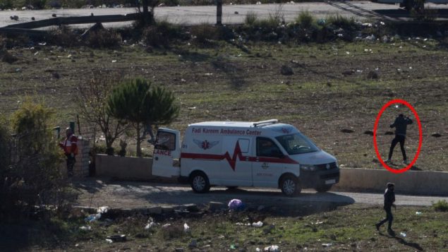 متظاهر فلسطيني يرشق الحجارة اثناء استخدام سيارة اسعاف كدرع خلال مظاهرات في رام الله، 9 ديسمبر 2017 (Israel Defense Forces)