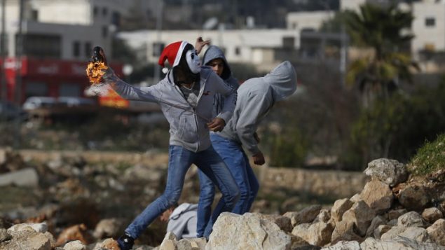 صورة توضيحية: متظاهرون فلسطينيون يلقون زجاجات حارقة باتجاه جنود اسرائيليين خلال اشتباكات في الضفة الغربية، 12 يناير 2018 (AFP PHOTO / ABBAS MOMANI)