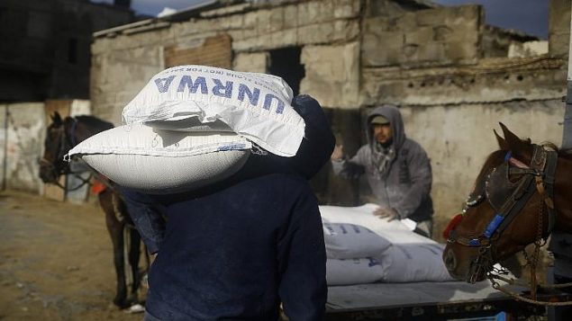 رجال فلسطينيون يحملون مساعدات غذائية امام مركز للأونروا في غزة، 15 يناير 2018 (AFP PHOTO / MOHAMMED ABED)