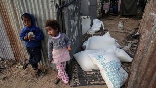 أطفال فلسطينيو يقفون بجانب أكياس مساعدات غذائية توفرها وكالة وكالة الأمم المتحدة لإغاثة وتشغيل اللاجئين الفلسطينيين في مخيم رفح للاجئين في جنوب قطاغ غزة، 24 يناير، 2017. (AFP Photo/Said Khatib)