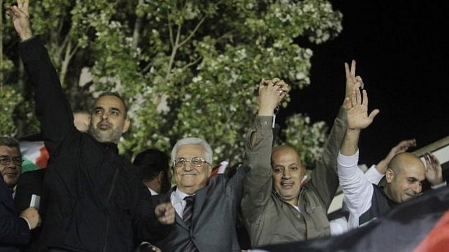 رئيس السلطة الفلسطينية محمود عباس، الثاني من اليسار،
 يلوح للجماهير وبرفقته أسرى فلسطينيون محررون من السجون الإسرائيلية خلال احتفالات في مقر عباس في مدينة رام الله في الضفة الغربية. (Issam Rimawi/Flash90)