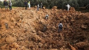 فلسطينيون يتفقدون موقعا لغارة جوية إسرائيلية في مدينة غزة، 18 فبراير، 2018. (AFP / MAHMUD HAMS)
