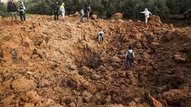فلسطينيون يتفقدون موقعا لغارة جوية إسرائيلية في مدينة غزة، 18 فبراير، 2018. (AFP / MAHMUD HAMS)