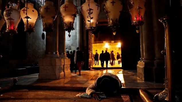 مصلون مسيحيون يصلون على حجر الطيب داخل كنيسة القيامة بعد إعادة فتح أبوابها في 28 فبراير، 2018، في أعقاب إغلاق استمر لثلاثة أيام احتجاجا على إجراءات ضريبية وقانون مقترح. (AFP / THOMAS COEX)