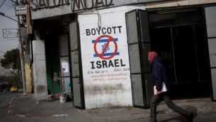 رجل فلسطيني يمر من أمام  رسم على جدار يدعو إلى مقاطعة إسرائيل في أحد شوارع مدينة بيت لحم في الضفة الغربية، 11 فبراير، 2015. (Miriam Alster/Flash 90)