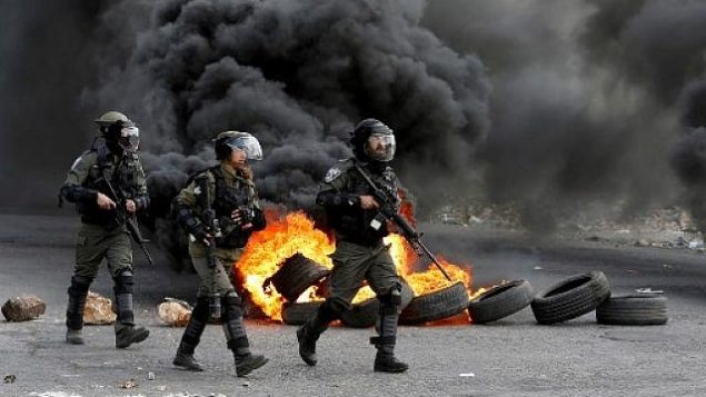 يتقدم حرس الحدود الإسرائيليون في شارع أثناء الاشتباكات مع المتظاهرين الفلسطينيين في أعقاب مظاهرة في مدينة رام الله بالضفة الغربية في 9 مارس 2018 ضد قرار الرئيس الأمريكي دونالد ترامب بالاعتراف بالقدس عاصمة لإسرائيل. (AFP/Abbas Momani)