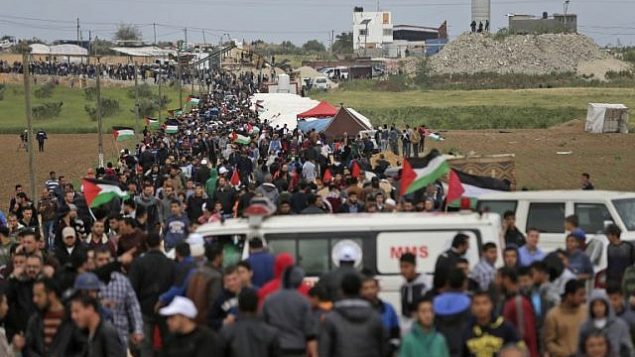 فلسطينيون يسيرون امام مدينة الخيام التي اقيمت امام الحدود مع اسرائيل شرقي مدينة غزة في يوم الارض، 30 مارس 2018 (AFP/ MAHMUD HAMS)