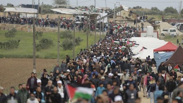 فلسطينيون يسيرون امام مدينة الخيام التي اقيمت امام الحدود مع اسرائيل شرقي مدينة غزة في يوم الارض، 30 مارس 2018 (AFP/ MAHMUD HAMS) فلسطينيون يسيرون امام مدينة الخيام التي اقيمت امام الحدود مع اسرائيل شرقي مدينة غزة في يوم الارض، 30 مارس 2018 (AFP/ MAHMUD HAMS)