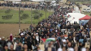 فلسطينيون يسيرون امام مدينة الخيام التي اقيمت امام الحدود مع اسرائيل شرقي مدينة غزة في يوم الارض، 30 مارس 2018 (AFP/ MAHMUD HAMS)