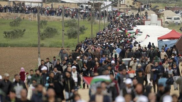 فلسطينيون يسيرون امام مدينة الخيام التي اقيمت امام الحدود مع اسرائيل شرقي مدينة غزة في يوم الارض، 30 مارس 2018 (AFP/ MAHMUD HAMS)