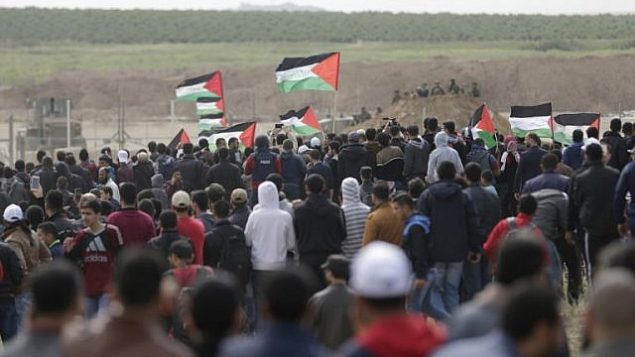 فلسطينيون يسيرون امام مدينة الخيام التي اقيمت امام الحدود مع اسرائيل شرقي مدينة غزة في يوم الارض، 30 مارس 2018 (AFP/ MAHMUD HAMS) فلسطينيون يسيرون امام مدينة الخيام التي اقيمت امام الحدود مع اسرائيل شرقي مدينة غزة في يوم الارض، 30 مارس 2018 (AFP/ MAHMUD HAMS)
