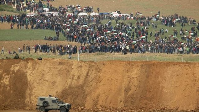 صورة التقطت من كيبوتس ناحال عوز جنوب اسرائيل، يظهر فلسطيني في الطرق الثاني من الحدود يشاركون في مظاهرة في ذكرى يوم الارض، 30 مارس 2018 (AFP PHOTO / Jack GUEZ) صورة التقطت من كيبوتس ناحال عوز جنوب اسرائيل، يظهر فلسطيني في الطرق الثاني من الحدود يشاركون في مظاهرة في ذكرى يوم الارض، 30 مارس 2018 (AFP PHOTO / Jack GUEZ)