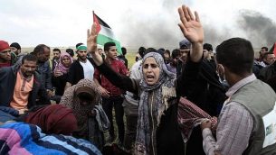 متظاهرون فلسطينيون يلوحون بعلمهم الوطني خلال مظاهرة تخلد ذكرى يوم الأرض، بالقرب من الحدود مع إسرائيل، شرق مدينة غزة  في 30 مارس / آذار 2018. (AFP/Mahmud Hams)