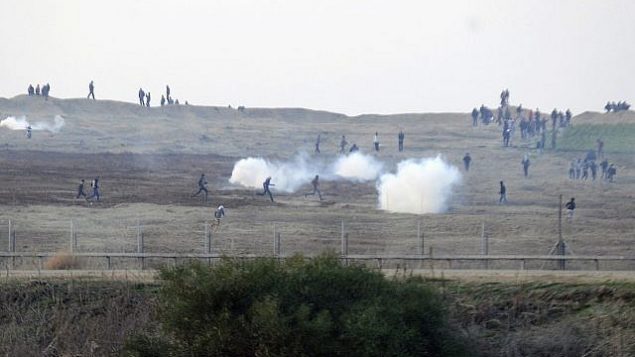 توضيحية: متظاهرون فلسطينيون بالقرب من السياج الحدود الإسراءئيلي مع قطاع غزة والجيش الإسرائيلي يطلق قنابل الغاز المسيل للدموع باتجاههم، 3 يناير، 2014. (David Buimovitch/Flash90)