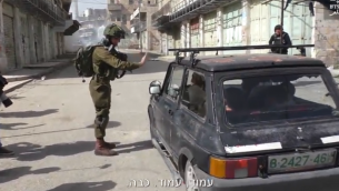 صورة لجندي إسرائيلي يقوم يإيقاف مركبة فلسطينية في مدينة الخليل في الضفة الغربية، 16 فبراير، 2018. (لقطة شاشة: YouTube)